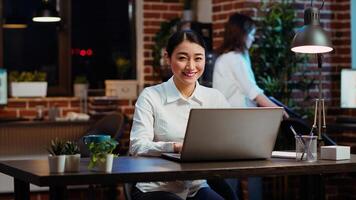 Zoom in on joyful asian employee writing important emails at computer desk, finalizing deal with business partners. Portrait close up shot of happy employee typing on laptop, camera B photo