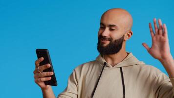 Modern guy answering videocall network and waving, meeting online on videoconference connection to discuss with his friends. Young arab person talking to people on remote chat. Camera 2. photo
