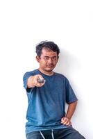 Adult man holding a TV remote, aiming to change the channel, isolated on a white background. Ideal for themes related to TV, media control, and home entertainment. photo