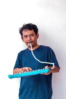 Adult man playing a melodica, isolated on a white background. The image shows a man enjoying music, perfect for themes related to music, instruments, and musical performance. photo