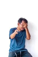 Adult man holding a TV remote, covering his eyes with his hand in fear, isolated on a white background. Perfect for themes related to fear, surprise, and emotional reactions. photo