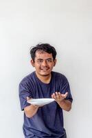 Adult man holding an empty white plate as if presenting food and smiling, isolated on white background. Ideal for themes related to cooking, food presentation, and positive emotions. photo