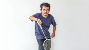 Adult male model in a gray t-shirt holding a badminton racket as if playing, isolated on a white background. perfect for themes related to sports, fitness, badminton, and athletic activities. photo