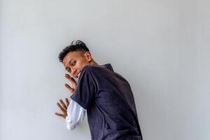 Adult man pushing against a plain white wall while facing away, isolated on a white background. The image captures a dynamic pose, ideal for themes related to strength, effort, and fitness. photo