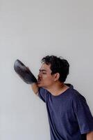 an adult man wearing a navy blue t-shirt is tasting food by slurping a frying pan isolated on white background photo