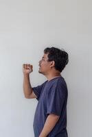 Adult man coughing isolated on a plain white background. The image shows a close-up of a man in casual attire, visibly distressed by a cough. photo