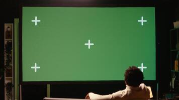 Man using green screen modern TV to watch news program broadcasting in living room. Person watching mockup ultrawide television display showing VOD channel, relaxing on couch photo