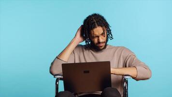 Middle Eastern man composing email, typing on laptop keyboard, struggling to think of what to write. BIPOC person sending mail online, brainstorming message idea, studio background, camera A photo