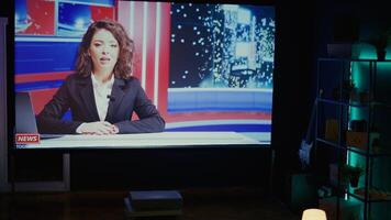 Anchorwoman on large TV screen showing reportages about summer vacations and artificial intelligence on streaming service channel. Widescreen television set left turned on, dolly out shot photo