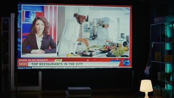 on demand cooking channel left open on widescreen television set in neon lit living room. Cord cutting streaming service food program broadcasted on smart TV in home theatre, jib up shot photo