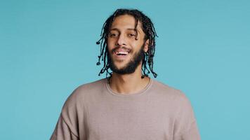 Approving smiling Middle Eastern man happily clapping hands, satisfied with accomplishments. BIPOC person cheering, doing praising gesture, isolated over blue studio background, camera B photo