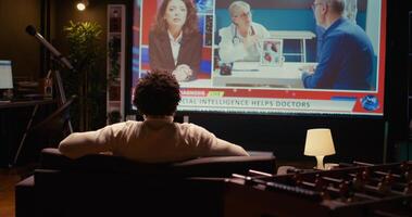 African american man watching news program on modern TV about artificial intelligence subject, zoom in close up shot. Cord cutter entertained by subscription service on ultrawide television screen photo