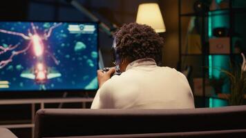 Gamer upset after receiving game over screen on TV display, getting his spaceship destroyed in huge explosion while fighting enemies. BIPOC man sad after losing science fiction spacecraft videogame photo