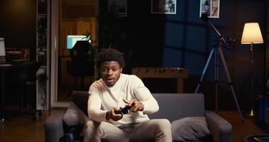 Man in neon lit home theatre playing games on couch, enjoying day off from work. Gamer battling enemies in online multiplayer shooter on gaming console, using motion controlled controller photo