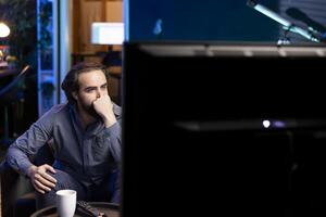 Person using TV to binge series on subscription based streaming services, enthralled by interesting movie. Man relaxing in apartment enjoying VOD shows on television display photo