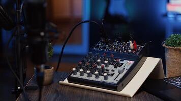 Close up shot of analog mixer and microphone used to produce impeccable sound quality during podcast recording in dimly lit studio. Cutting edge audio recording equipment on table in apartment photo