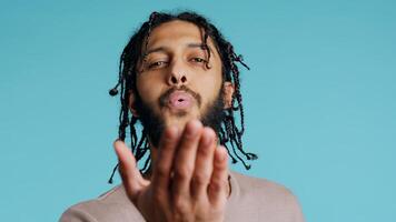 Middle Eastern frisky playful man blowing kisses to camera, being flirty. Lively charming BIPOC person having fun sending air kisses, doing romantic gesturing, studio background, camera B close up photo