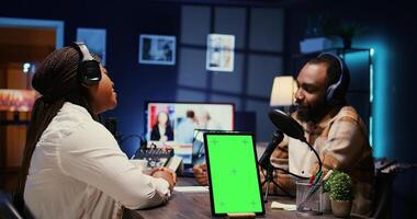 Isolated screen tablet next to cohosts streaming podcast using professional vlogging gadgets on vlog channel. Chroma key device between podcasters meeting in studio to film show photo