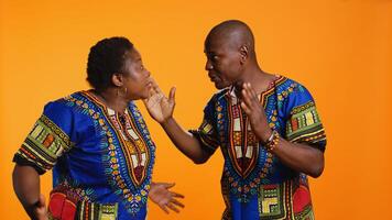 Angry ethnic woman shouting at her husband and arguing in front of camera, yelling and causing huge argument. Partner feeling tired of fighting and is ignoring his wife by covering his ears. photo
