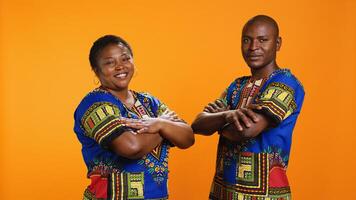 Confident ethnic couple posing in studio with colorful clothes, presenting traditional african american attire and being proud about their culture. Smiling husband and wife with arms crossed. photo