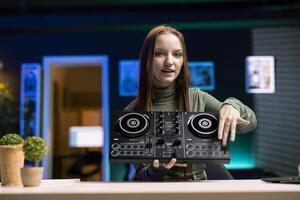 Portrait of girl mixing on DJ turntables, doing music production tutorial for internet streaming channel. Gen Z content creator playing around with stereo sound mixer in studio photo