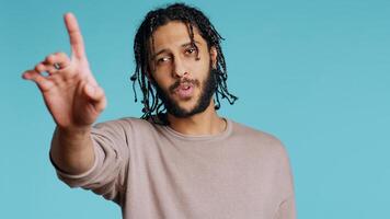 Assertive Middle Eastern man doing stop hand gestures. Annoyed BIPOC person doing firm halt sign gesturing, wishing to end concept, isolated over blue studio background, camera B photo