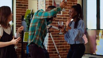 Asian, african american and caucasian group of friends dancing at apartment party, entertaining themselves, feeling the rhythm. Diverse colleagues doing energetic dance moves on bouncy music photo