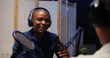 African american man recording podcast using high tech audio equipment to interview guest, ensuring flawless sound quality for subscribers listening at home interested in interviewee photo
