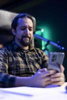 Young man with a concentrated expression, texting on his cell phone, sending messages, and checking social media. Focused male individual browsing the internet on his mobile device. photo