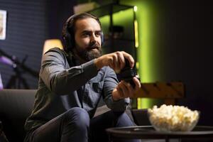 Man playing videogames using controller, having fun in green neon illuminated room. Gamer competing in online multiplayer game on gaming console using gamepad, talking with friends through headset photo