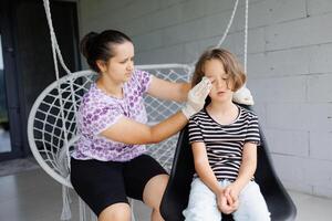 a small childhood infection on the eyelid caused by insect, mosquito or bee bites that causes swelling, redness, heat and itching. A mother is trying to remove swelling from a child's eye photo