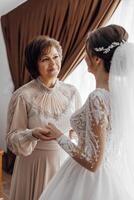 Daughter who became the bride gently embraces her mother. Mother of the bride blesses the bride for a happy family life. photo