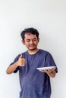 Adult man holding an empty white plate while giving a thumbs up and smiling, isolated on white background. Perfect for themes related to cooking, food presentation, and positive emotions. photo