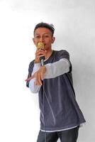 Young expressive singer happy man wearing gray t-shirt singing song into microphone in karaoke club spreading hands isolated on plain white background studio portrait. People's lifestyle concept photo