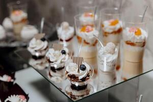 A table with a variety of desserts in plastic cups, including some with blueberries and raspberries photo