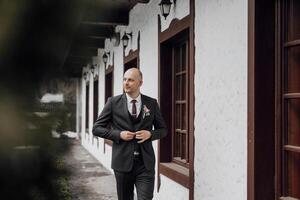 A man in a suit is standing in front of a building, adjusting his tie. Concept of formality and professionalism, as the man is dressed in a suit and tie photo