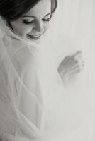 A bride is posing for a picture with her veil pulled back. She is smiling and looking at the camera photo