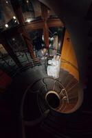 A bride and groom are standing on a spiral staircase. The bride is wearing a white dress and the groom is wearing a suit. They are both smiling and looking at the camera photo