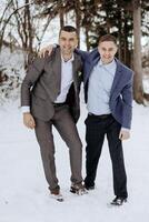Two men in suits are posing for a picture in the snow. One of them is wearing a tie photo