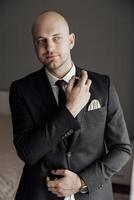 A man in a suit and tie is wearing a watch and holding a small object in his hand photo