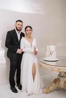 A man and woman are posing for a picture in front of a cake with the letter H on it photo