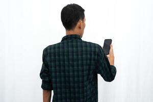 Back view of a man looking to the mobile phone that he hold photo