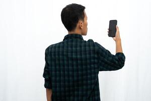 Back view of a man looking to the mobile phone that he hold photo