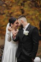 A bride and groom are posing for a picture with their hands together and the bride is giving the man a thumbs up photo