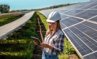 Beautiful female engineer wearing a white helmet and glasses monitoring solar panels on a tablet.Generated image photo