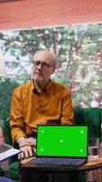 Vertical Nurse giving professional advice to her senior patients next to green screen on laptop, consulting elderly couple during a social visit. Medical assistant offering support and medicaments. Camera B. video