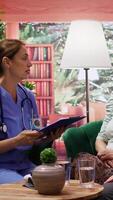 Vertical Nurse consulting a sick elderly man with oxygen tube and IV drip bag at home, paying a visit to offer assistance and support. Caregiver using an oximeter to examine health condition. Camera B. video