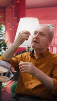 Vertical Elderly man applying rejuvenating serum and UV protection as a daily routine for skincare and anti aging, cosmetology. Senior person using cream moisturizer on his aging face, grooming. Camera B. video