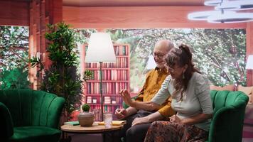 Elderly couple putting effervescent vitamin pill in a glass of water, preparing their medication at home. Happy people feeling good and optimistic about retirement, daily medicament dose. Camera B. video