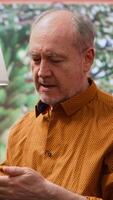 Vertical Elderly man applying serum and moisturizing cream on his cheeks, pampering skincare daily routine to preserve aging skin. Person using rejuvenating lotion for grooming, personal care. Camera A. video